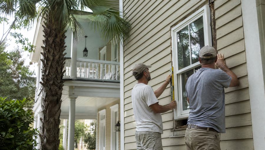 Installers leveling a new double-hung window on a Charleston single house